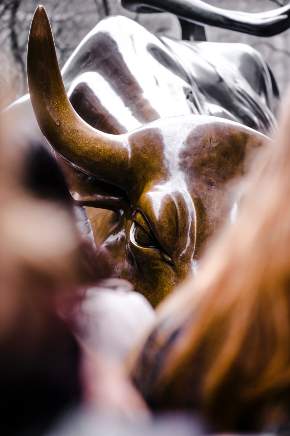 Change Finance -  - View on charging bull bronze statue on Wall street through a blurry crowd of people